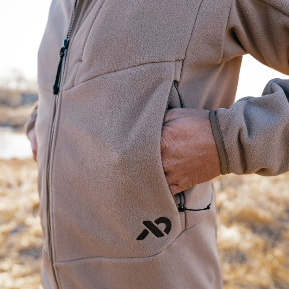 Tan fleece full-zip jacket, hand in side pocket with pull tab, and black logo.