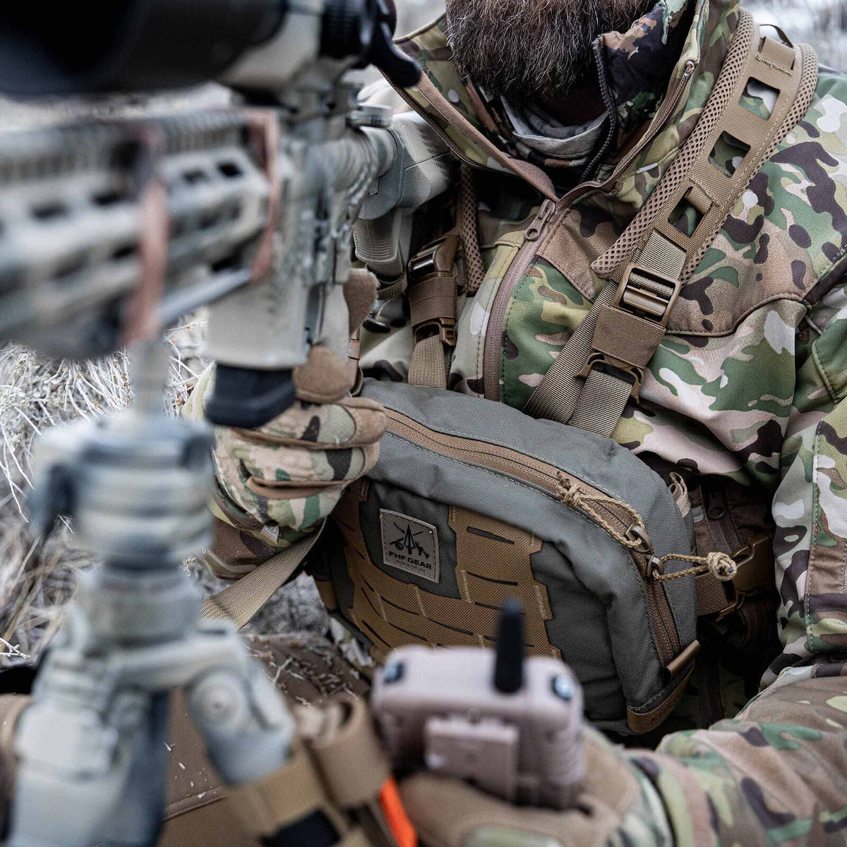 Olive green chest rig with tan MOLLE webbing and an FHF Gear logo patch, worn by a person aiming a rifle.
