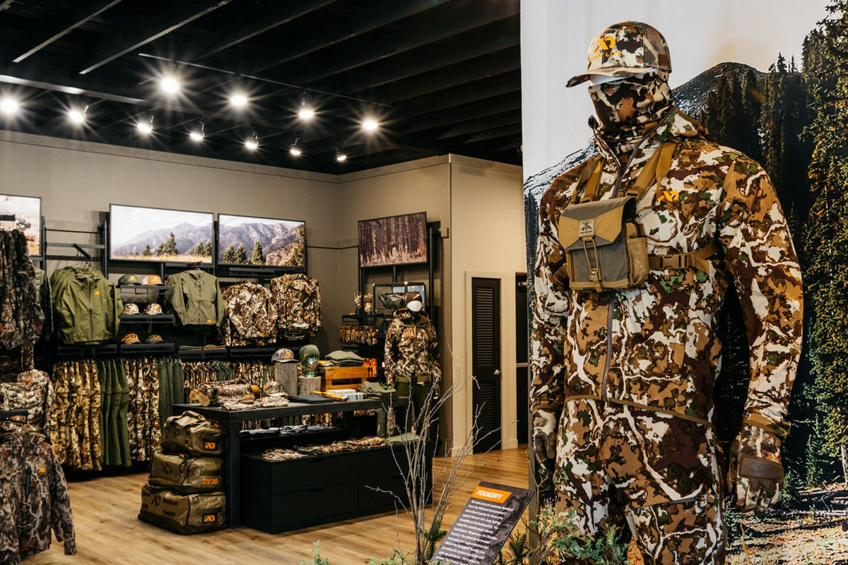 Multi-tone camo hunting suit on mannequin with hat, face mask, chest pack.