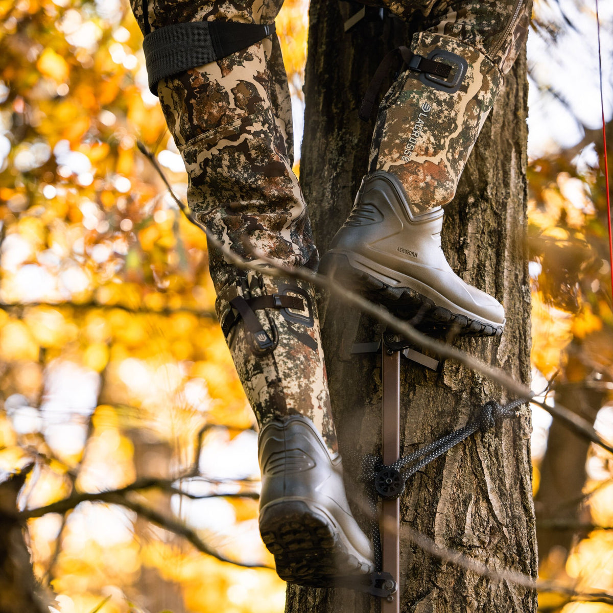 Walnut LaCrosse AeroForm rubber boots with camouflage uppers and rugged soles are seen climbing a tree stand.