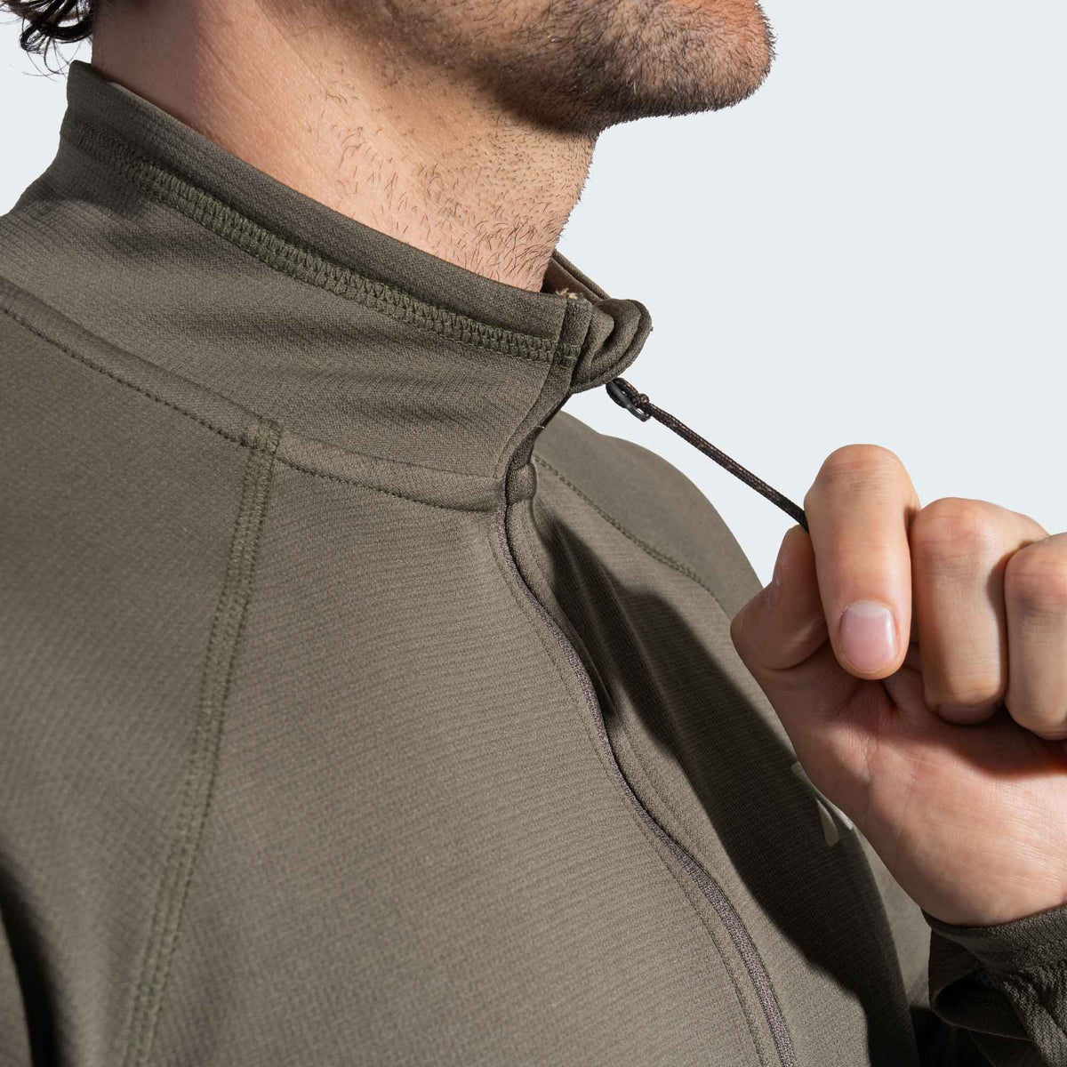 Person wearing a green quarter zip with a close-up of the zipper.