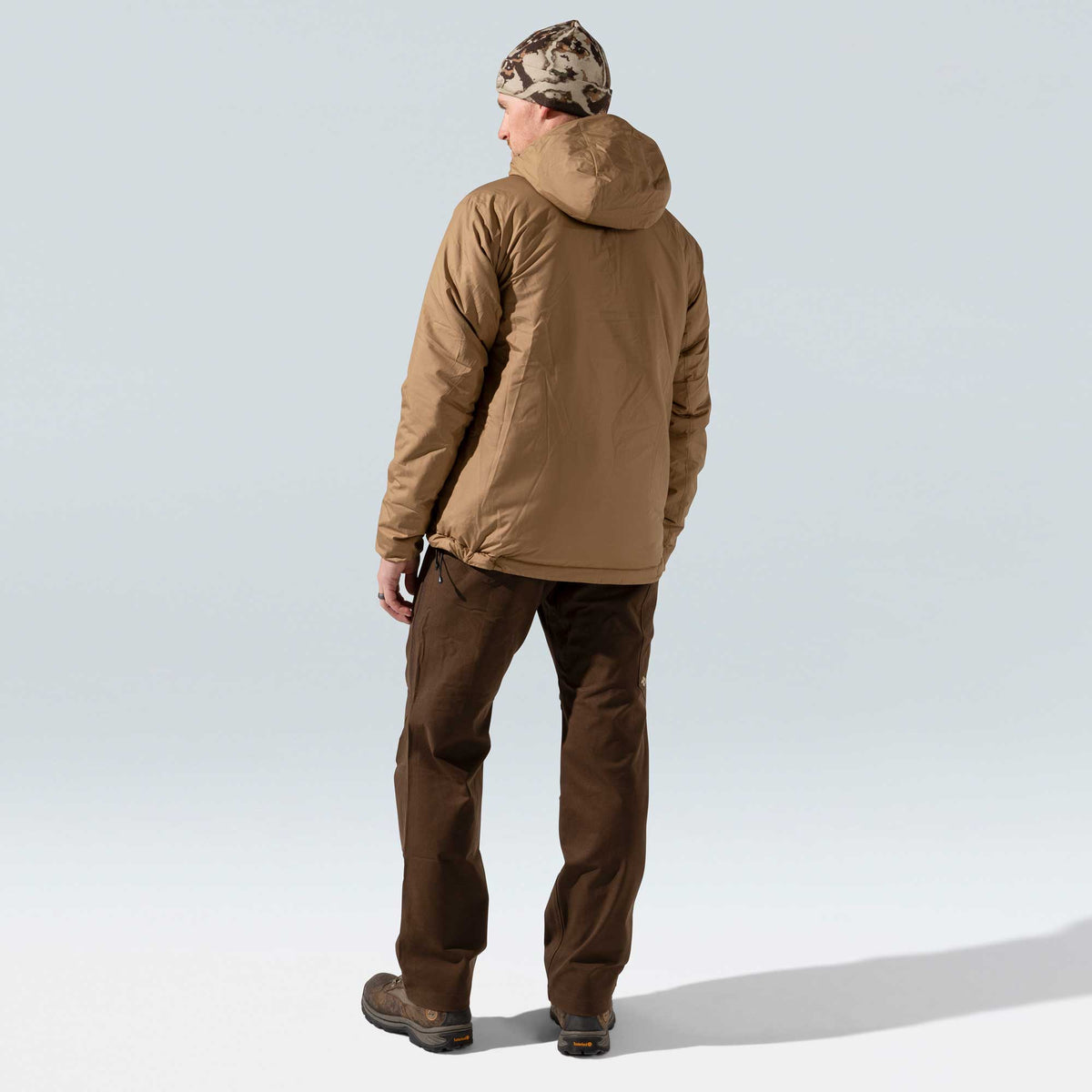Rear view of a person wearing a coyote brown hooded insulated jacket.