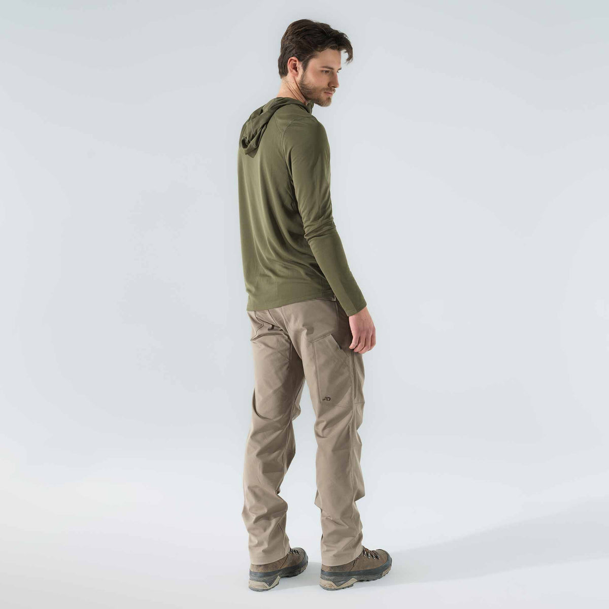 A man models an olive green long-sleeve hooded shirt and tan cargo pants featuring a thigh pocket with a small logo.