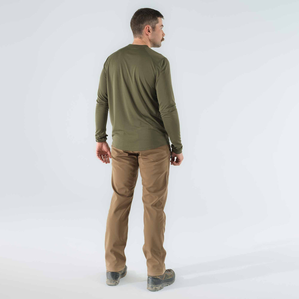 Rear view of a man wearing an olive green long-sleeve crew neck shirt and tan pants.