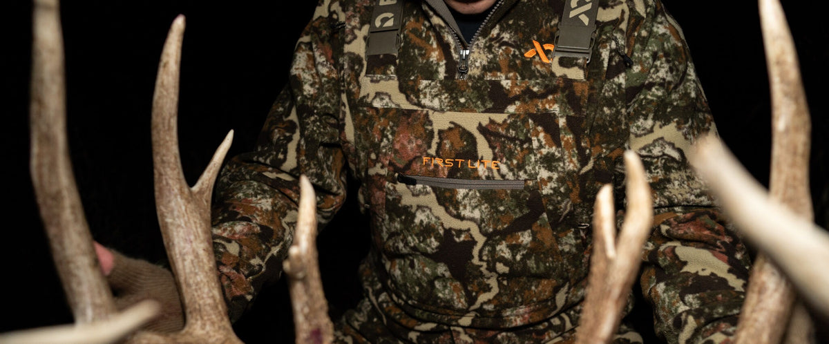 First Lite camo fleece quarter-zip with orange logo, zip pocket & suspenders.