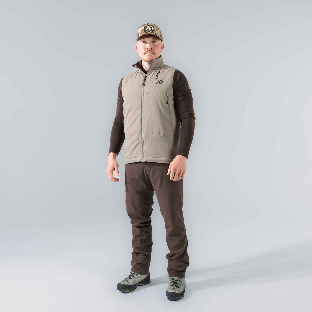 Tan insulated vest with a full zip, high collar, and zippered pockets worn by a man.