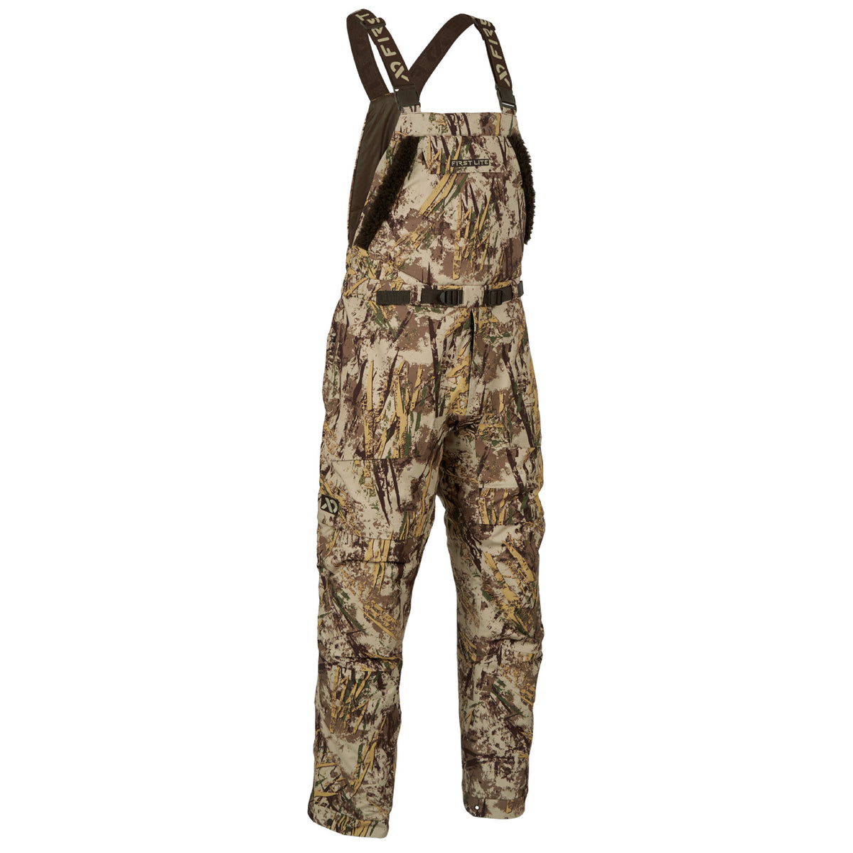 First Lite hunting bibs in a tan, brown, and green camouflage pattern, with dark brown adjustable shoulder straps, faux fur chest trim, and a waist belt.