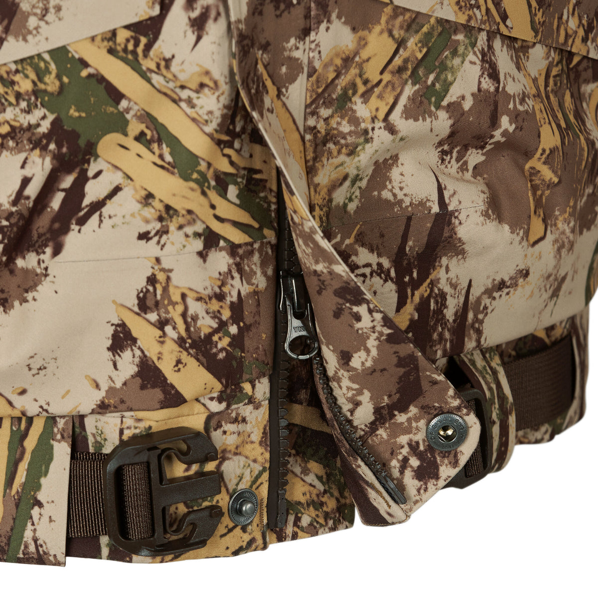 Close-up of a beige, brown, green, and yellow camouflage jacket featuring an open zipper, snap buttons, and an adjustable strap with a dark buckle at the hem.