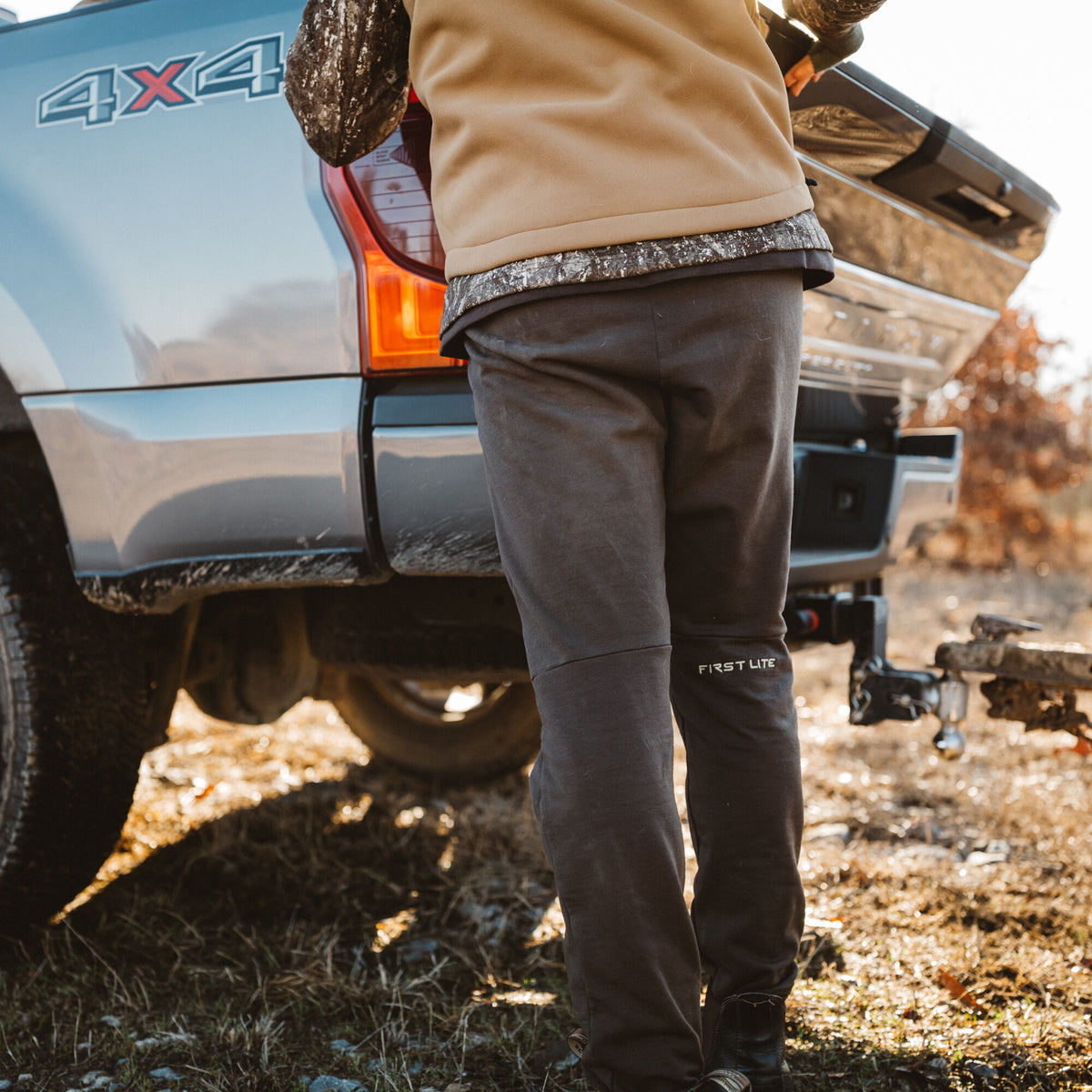 Dark gray First Lite outdoor pants with logo on lower left leg.