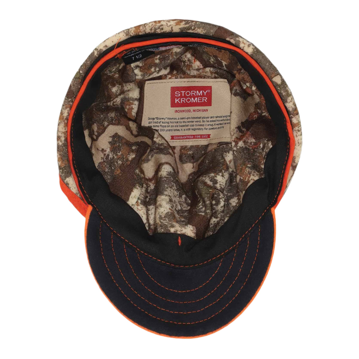 Camouflage baseball cap with orange trim, dark brim with orange stitching, and an interior Stormy Kromer brand label.