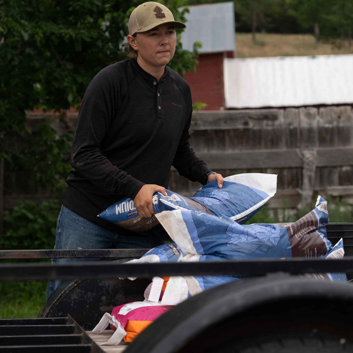 A person loads blue and white bags of Redmond mineral onto a trailer.