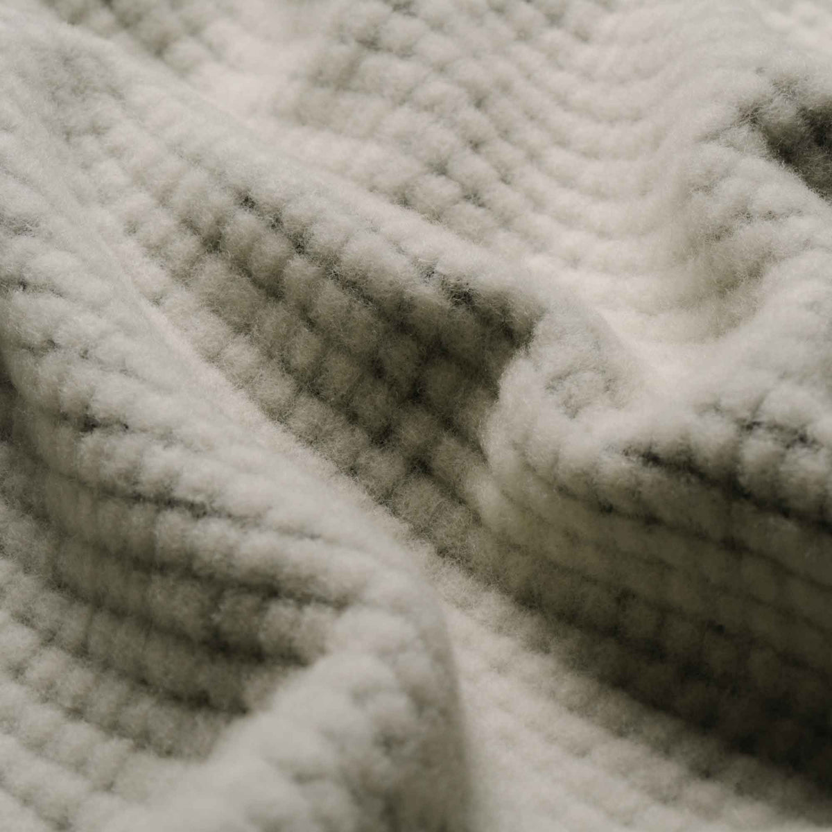Close-up of light grey fuzzy ribbed fabric with darker material visible between the ribs.