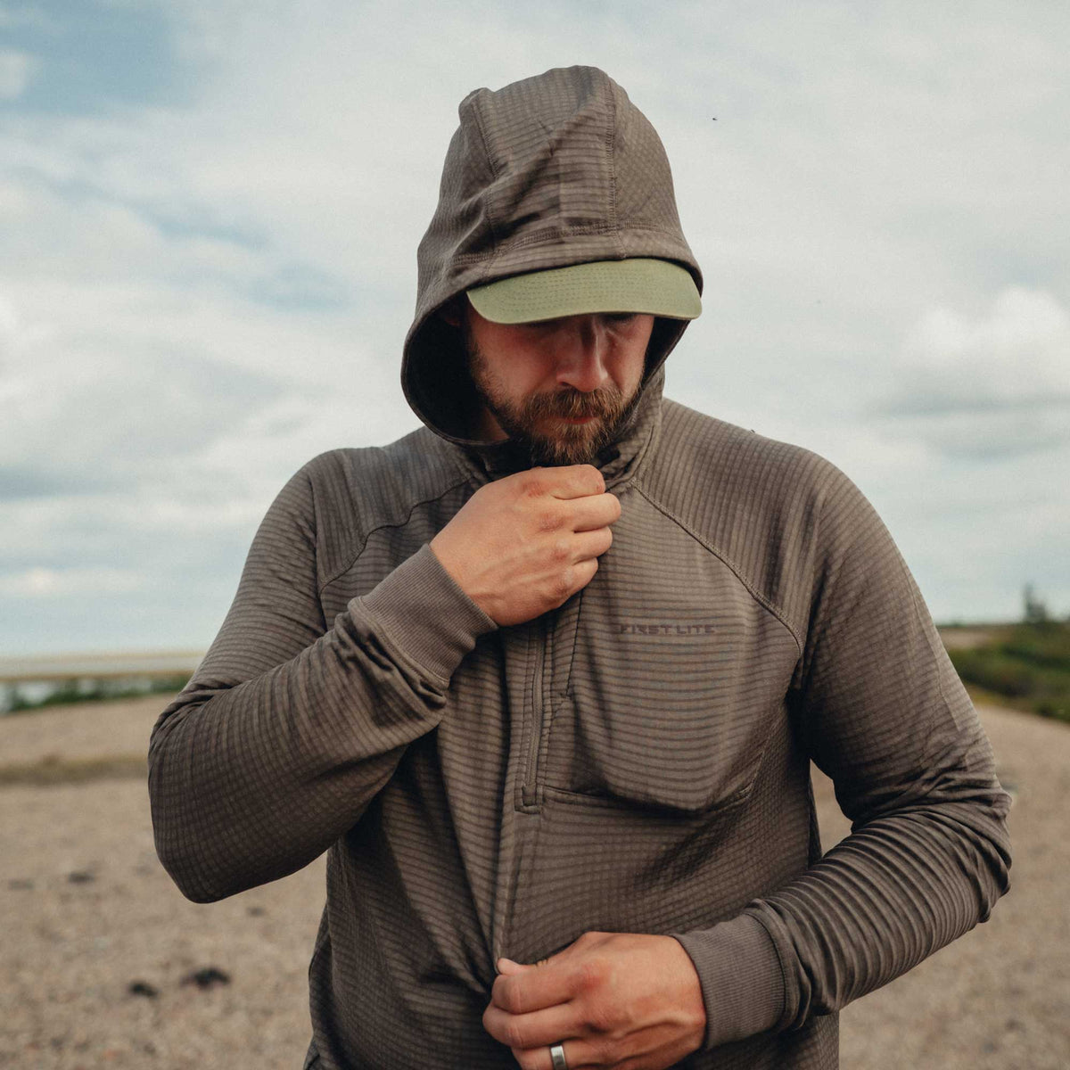Dark olive horizontally ribbed quarter-zip hoodie featuring a hood, ribbed cuffs, and "FIRST LITE" chest logo.
