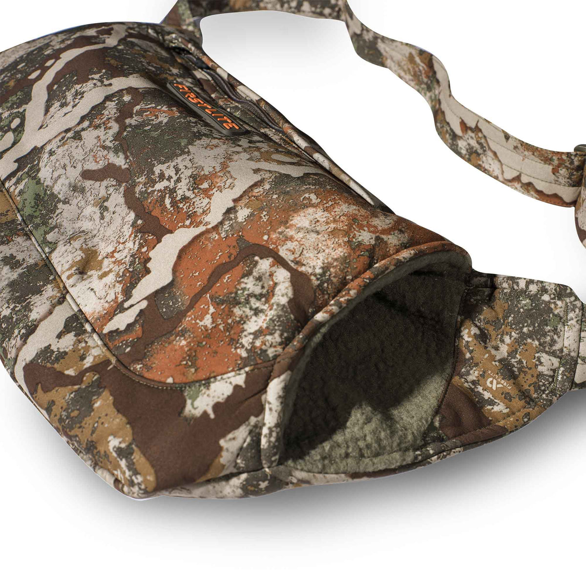 First Lite Fusion camouflage hand muff with a zippered pocket, fleece-lined opening, and shoulder strap.