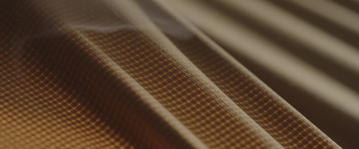 Brown ripstop fabric draped, showing its golden grid pattern.