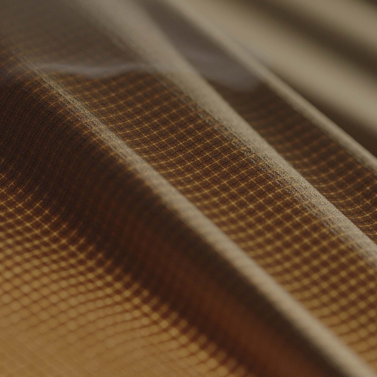 Draped brown ripstop fabric with a visible light-colored grid pattern.