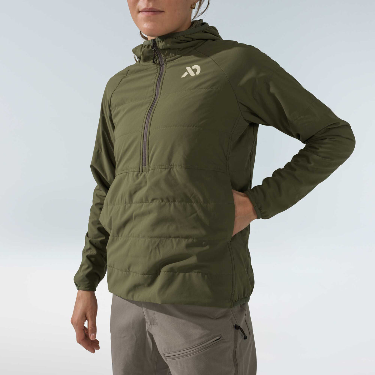 Olive green hooded half-zip anorak with a quilted torso, smooth sleeves, and a light chest logo.