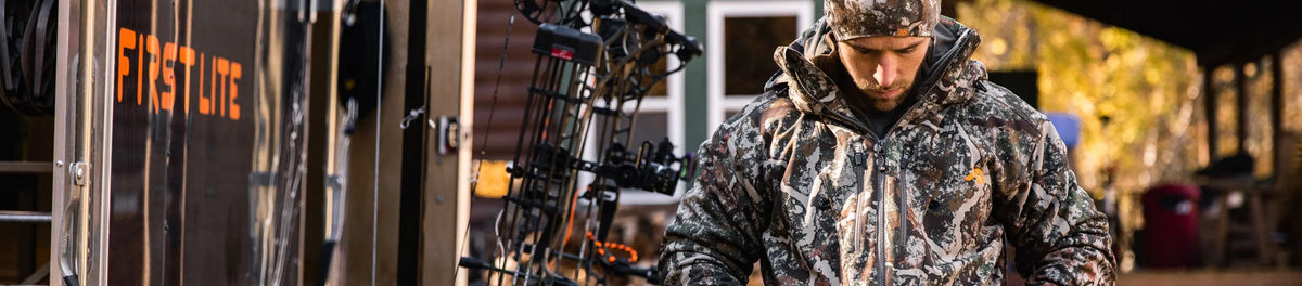 Man in First Lite Fusion camo hooded hunting jacket with orange logo and matching hat.