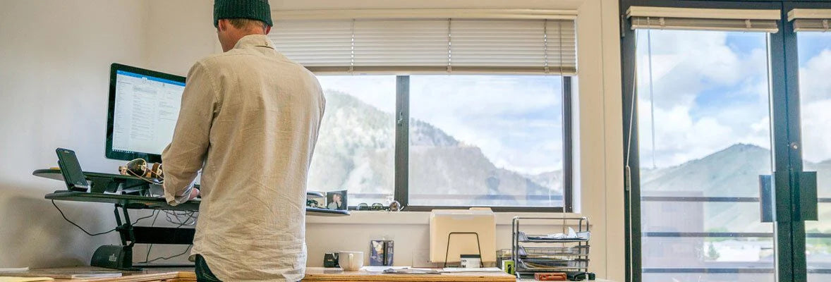 Black adjustable standing desk converter holding a monitor and smartphone.