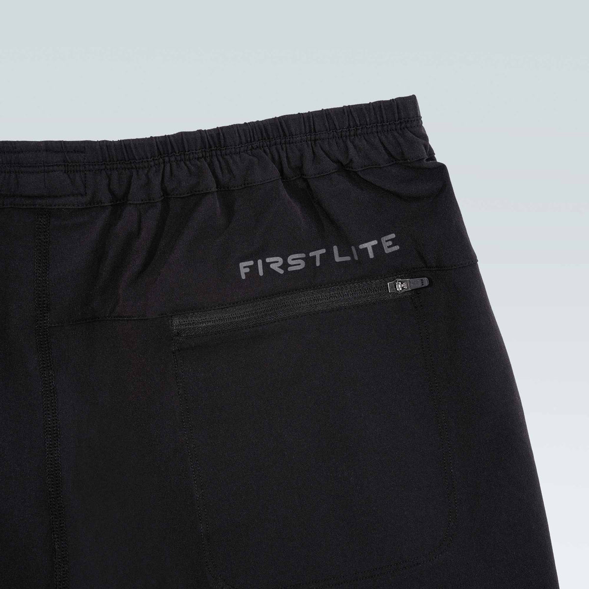 Black pants with 'First Lite' branding on a light gray background