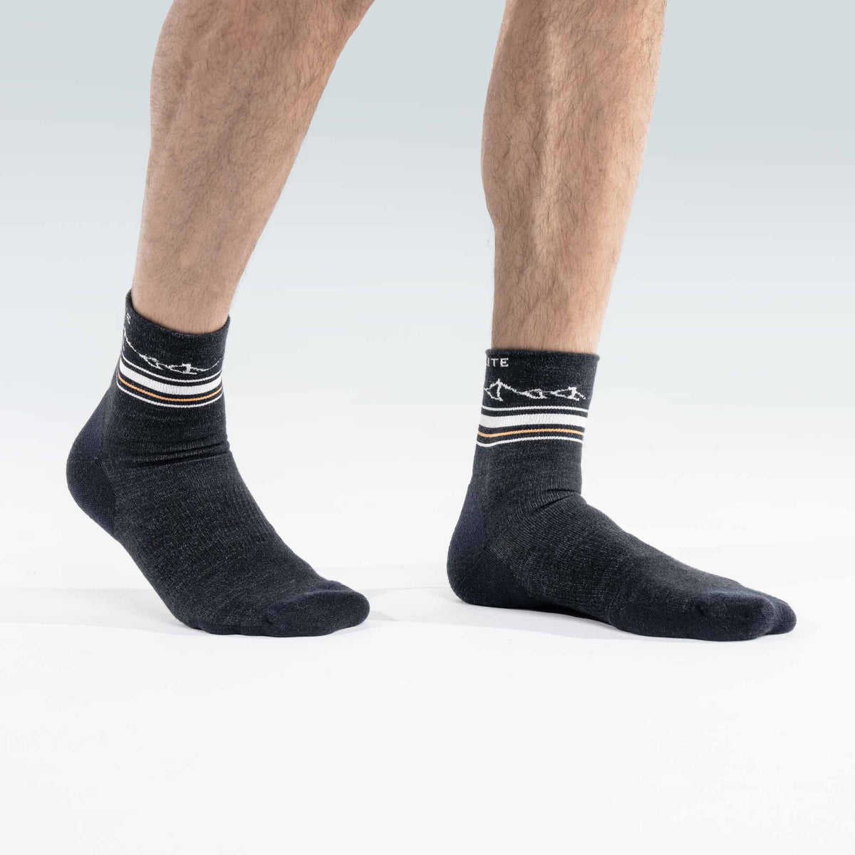Black socks with white and orange stripes worn by a person on a light gray background