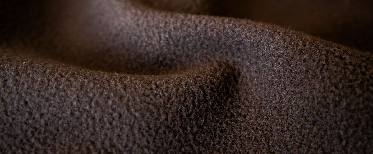 Dark brown fleece fabric with a soft, fuzzy texture and gentle folds.