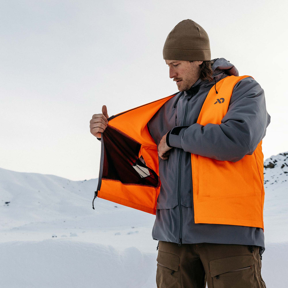 Grey jacket with bright orange integrated vest, shown open to reveal an interior mesh pocket and a black logo.