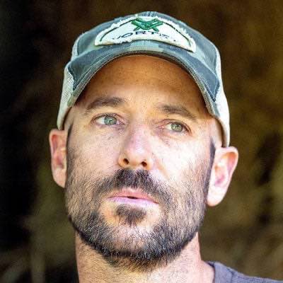 Camouflage trucker cap with white mesh and green logo patch.