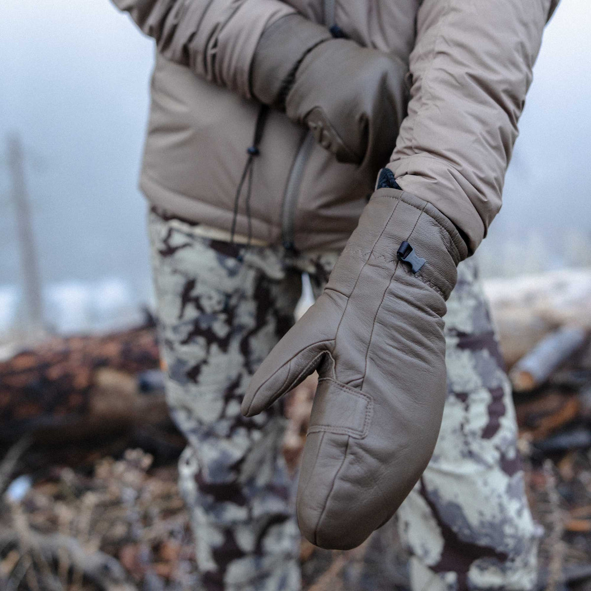 Taupe leather mittens featuring a black buckle on the cuff.