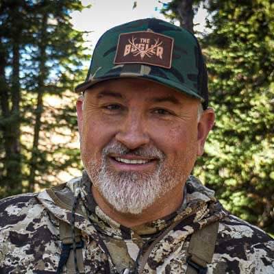 Green camo hat with "THE BUGLER" antler and arrow patch.