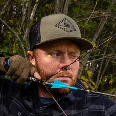 Olive green trucker hat with black mesh and a diamond deer logo.