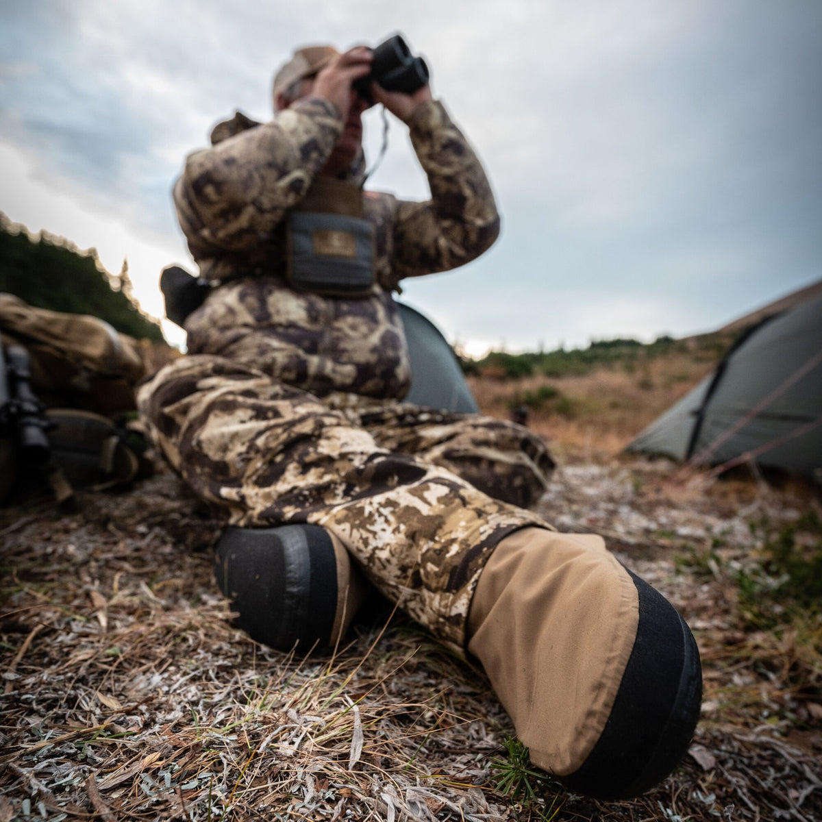 Two-tone tan and black gaiters worn over pants by a person sitting outdoors.