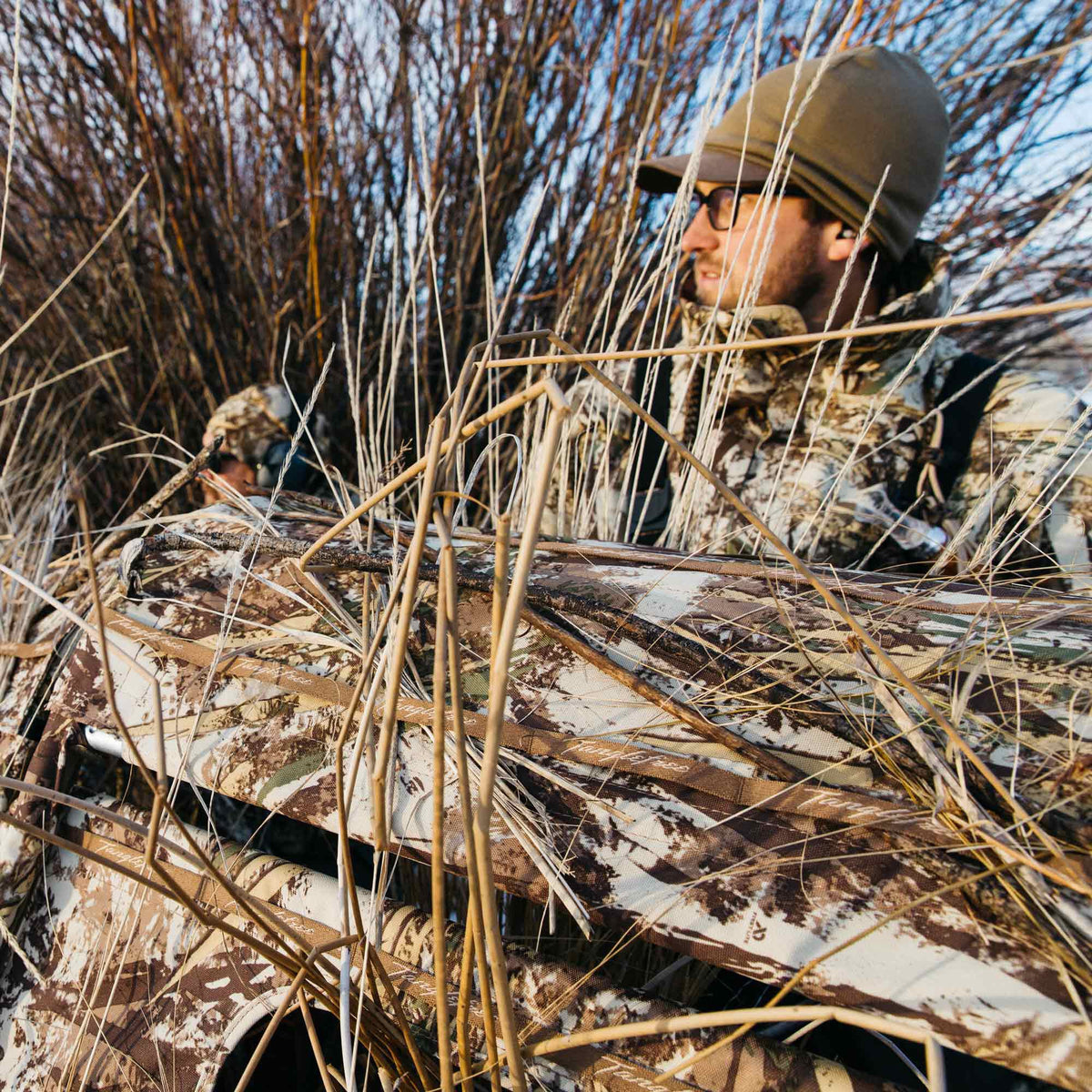 Tanglefree brown and tan camouflage hunting blind concealed in dry reeds with a hunter looking out.
