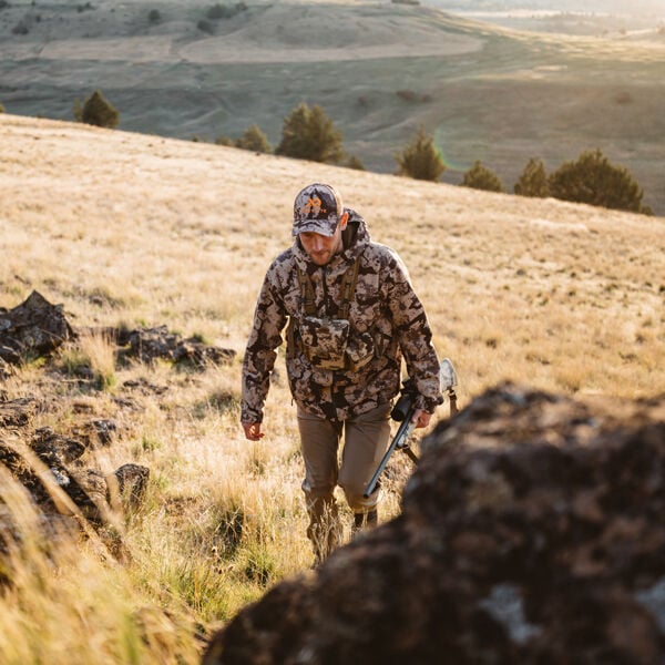 Men's earth-toned camo hooded jacket, cap, and chest harness.