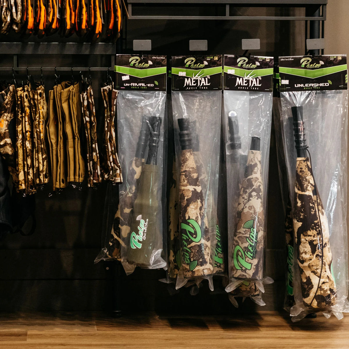 Phelps camouflage bugle tubes in packaging hang on a shelf with other hunting gear.