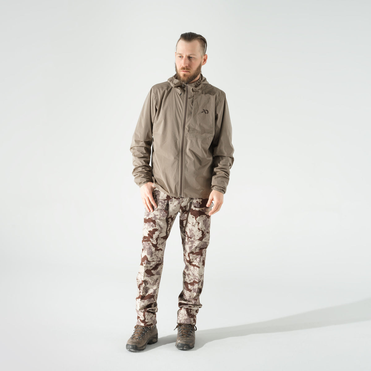 Man in a taupe hooded full-zip jacket and brown desert camouflage cargo pants.