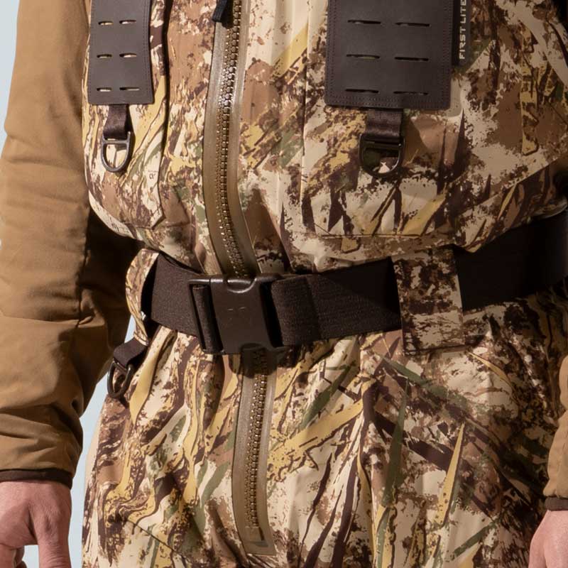 Camouflage waders with front zipper, black belt, and brown suspenders with D-ring.