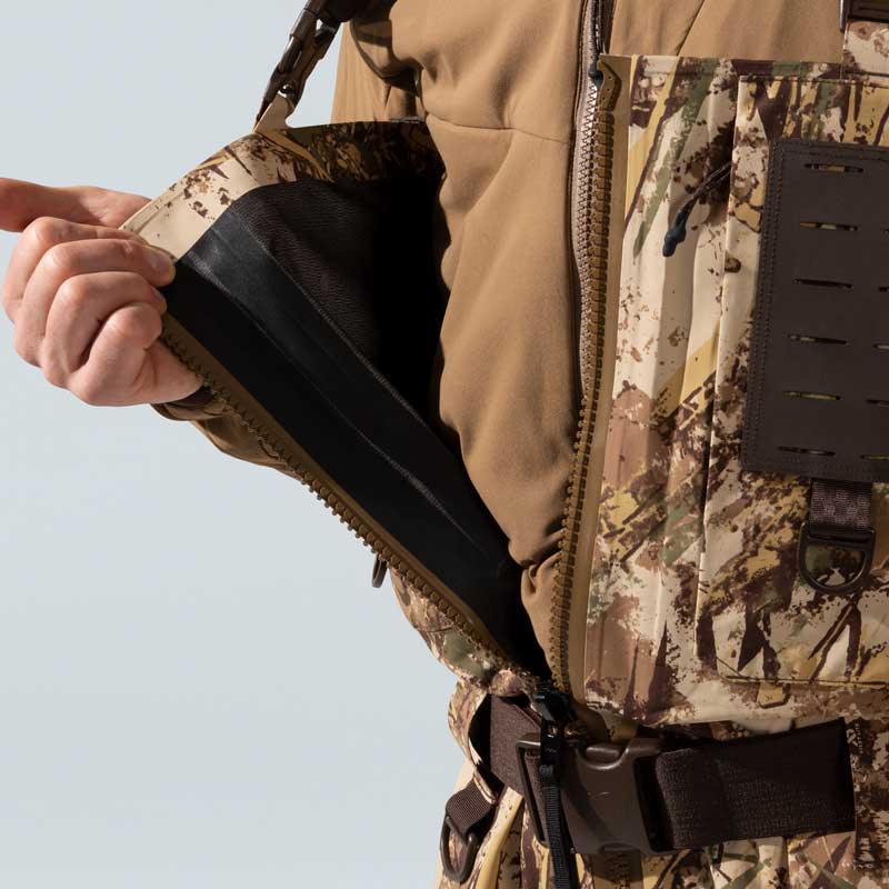 Camo waders with open side zipper revealing black waterproof gusset and chest pocket.