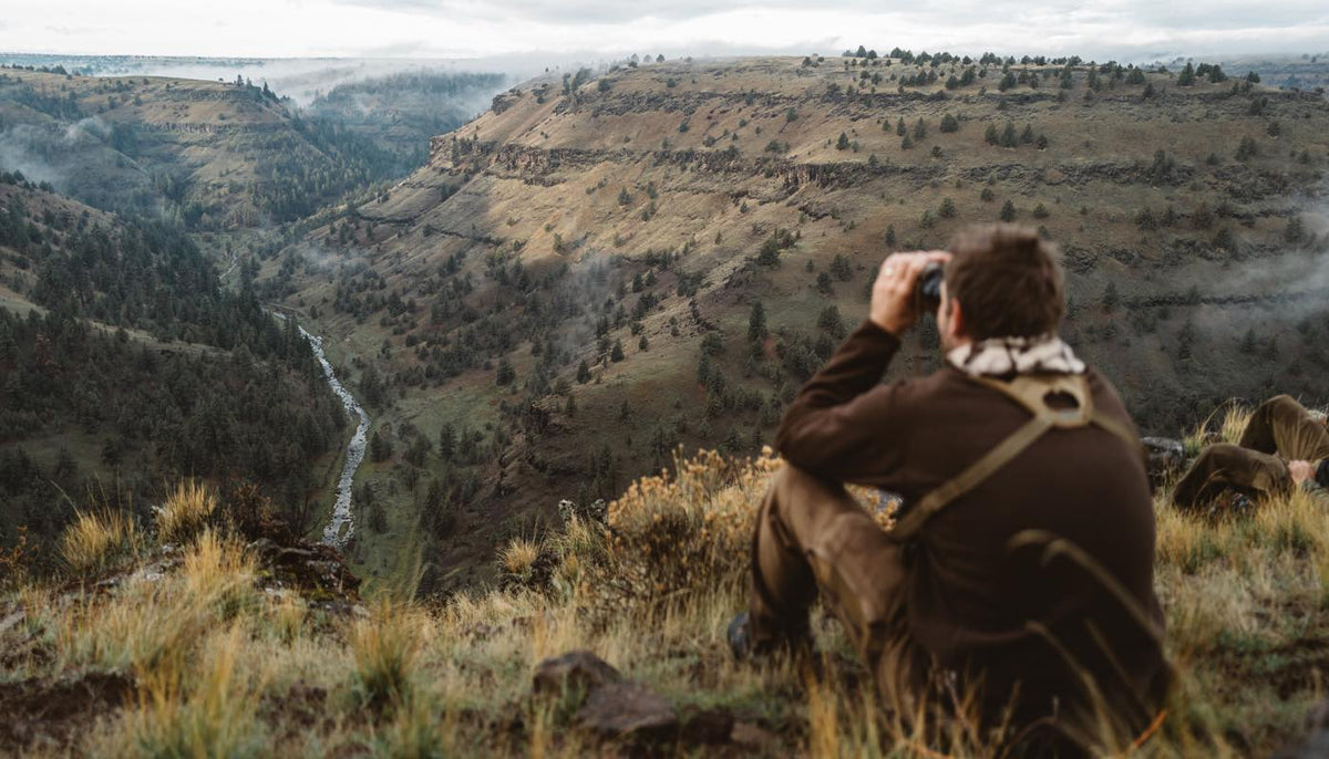 Tan binocular chest harness worn by man viewing a scenic canyon.