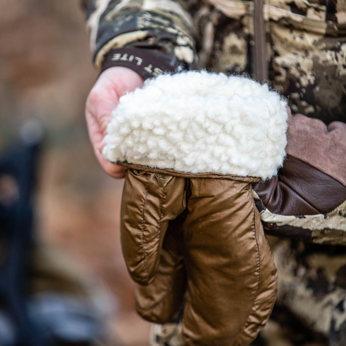Bronze-brown quilted mitten with a cream faux fur cuff, dark brown leather palm, and a small woven loop.