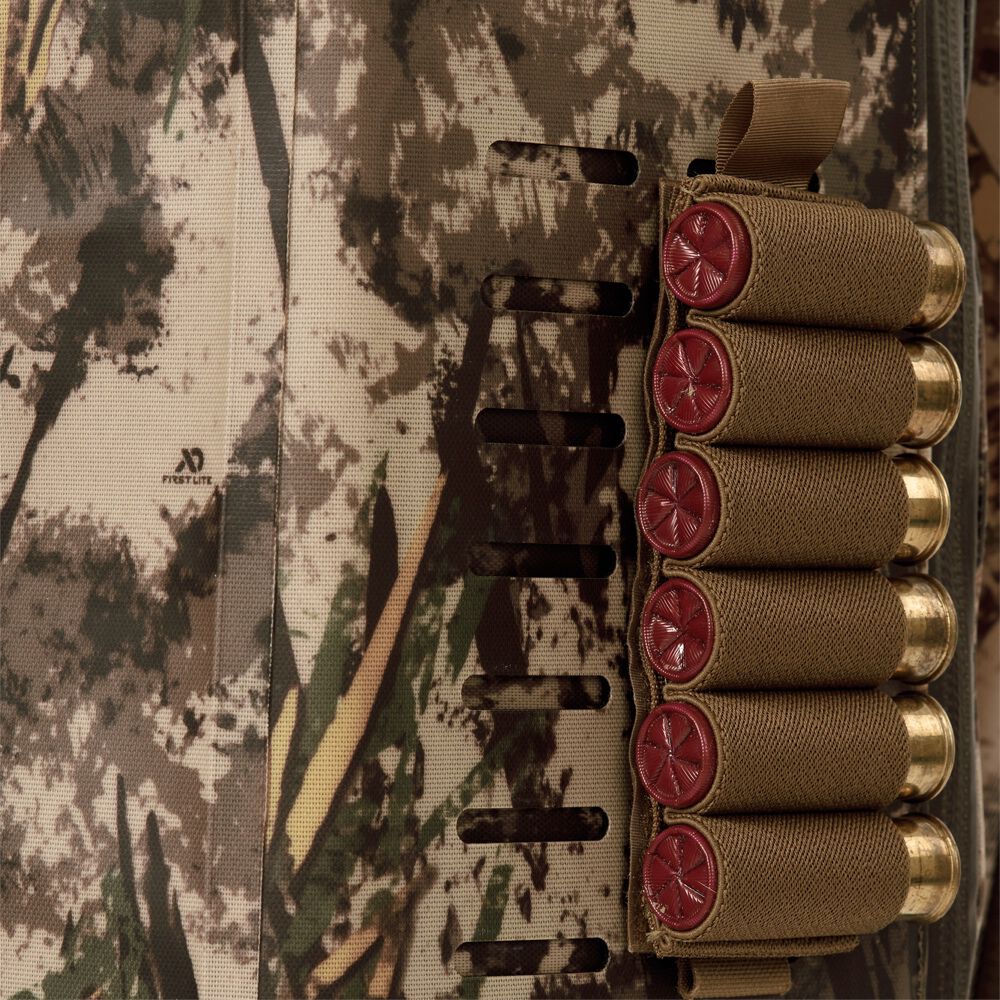Coyote brown six-shell holder with red-tipped shotgun shells attached to First Lite camouflage fabric.