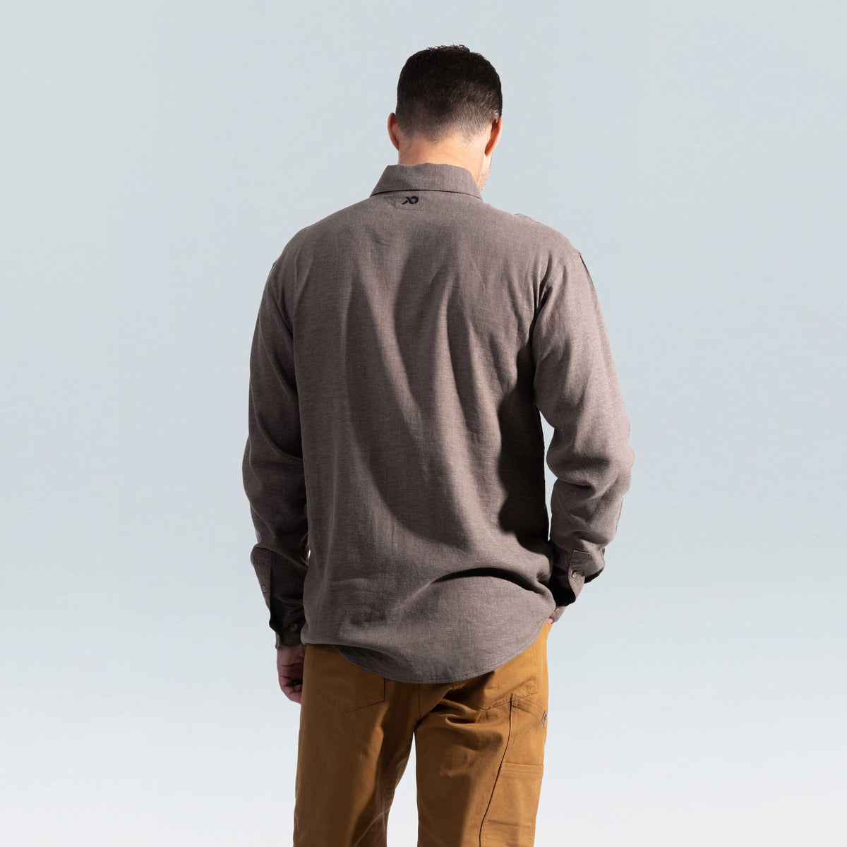 Person wearing a brown shirt and tan pants against a light gray background