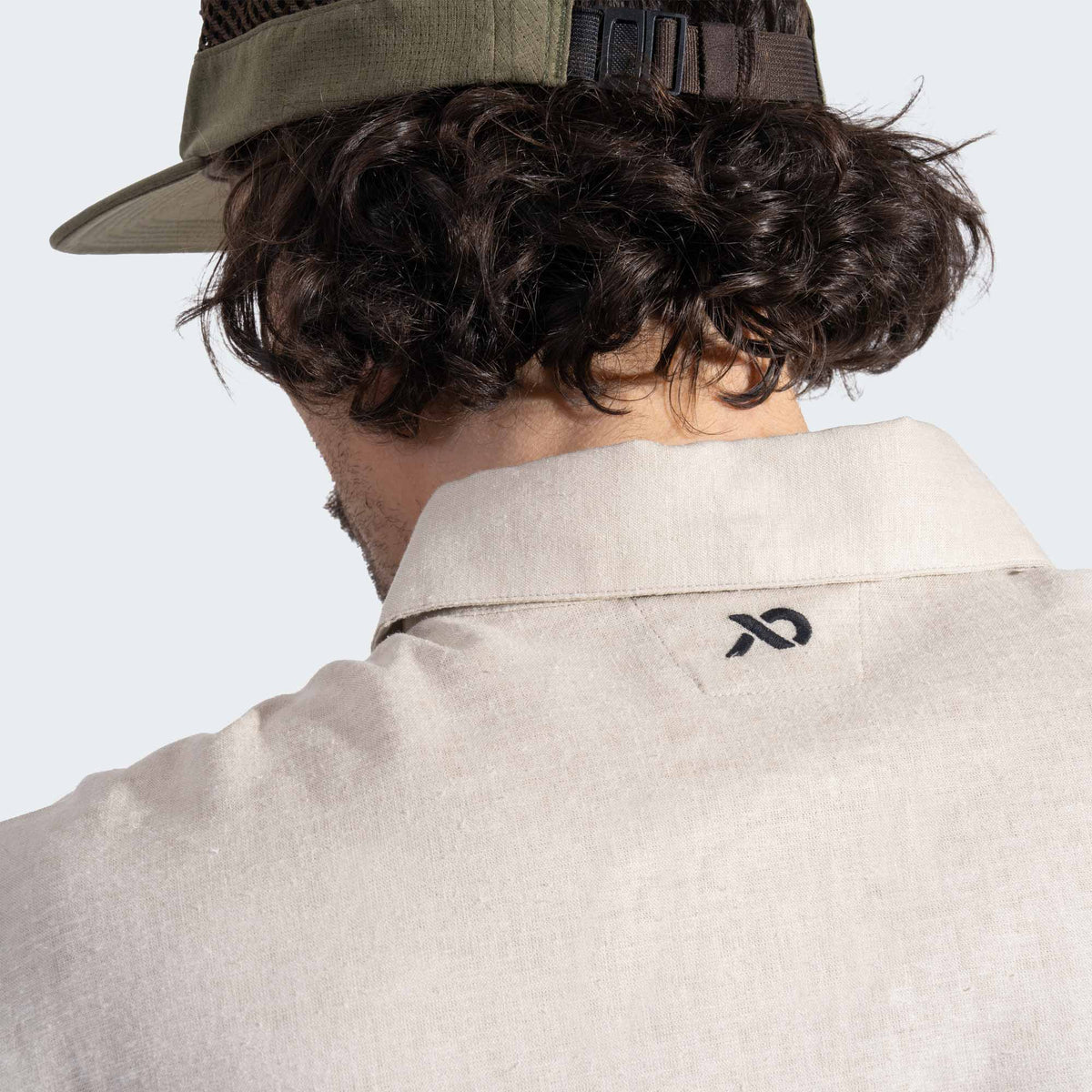 Person wearing a beige shirt with a First Lite logo on the collar against a light background