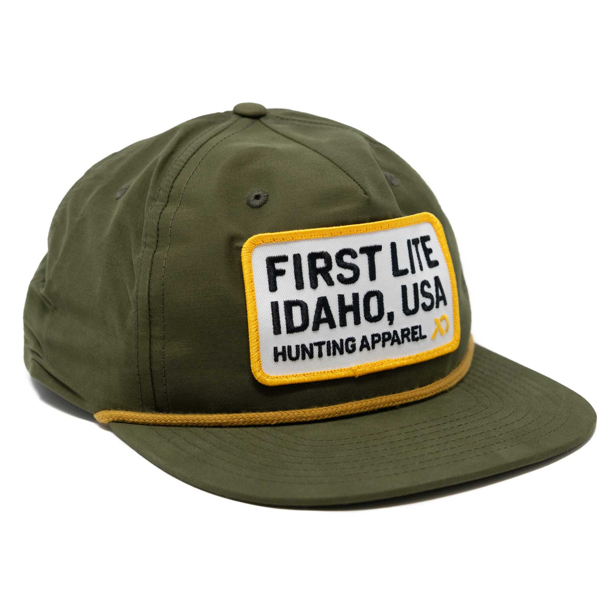 Olive green cap with a white patch featuring "FIRST LITE IDAHO, USA HUNTING APPAREL" in black text, and a yellow rope above the brim.