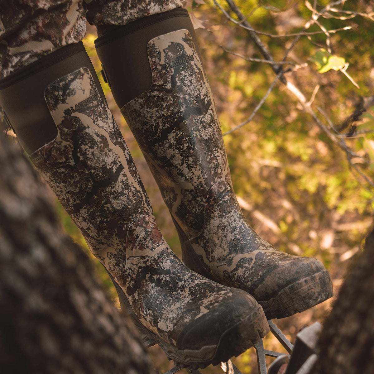 LaCrosse camouflage rubber hunting boots with dark brown tops and rugged soles are worn in a tree stand.