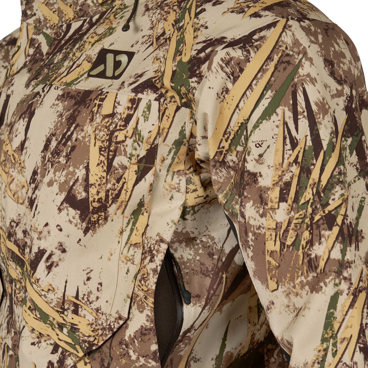Camouflage hunting jacket with a tan, brown, and green reed pattern, featuring a zipped chest pocket and First Lite logo.