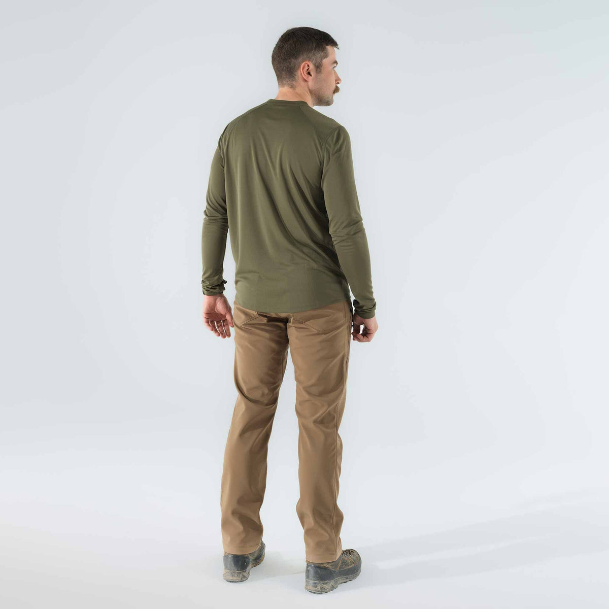 A man wearing an olive green long-sleeve raglan shirt and tan pants, viewed from behind.