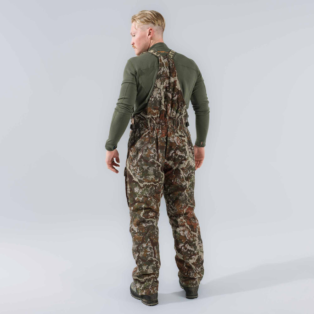 Camouflage hunting bibs with FIRSTLITE branded shoulder straps and an elasticized back waist.