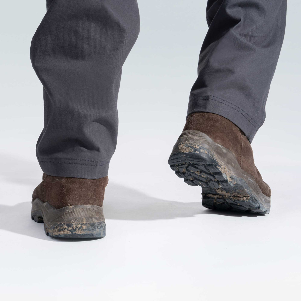 Brown work boots with worn soles on a white background
