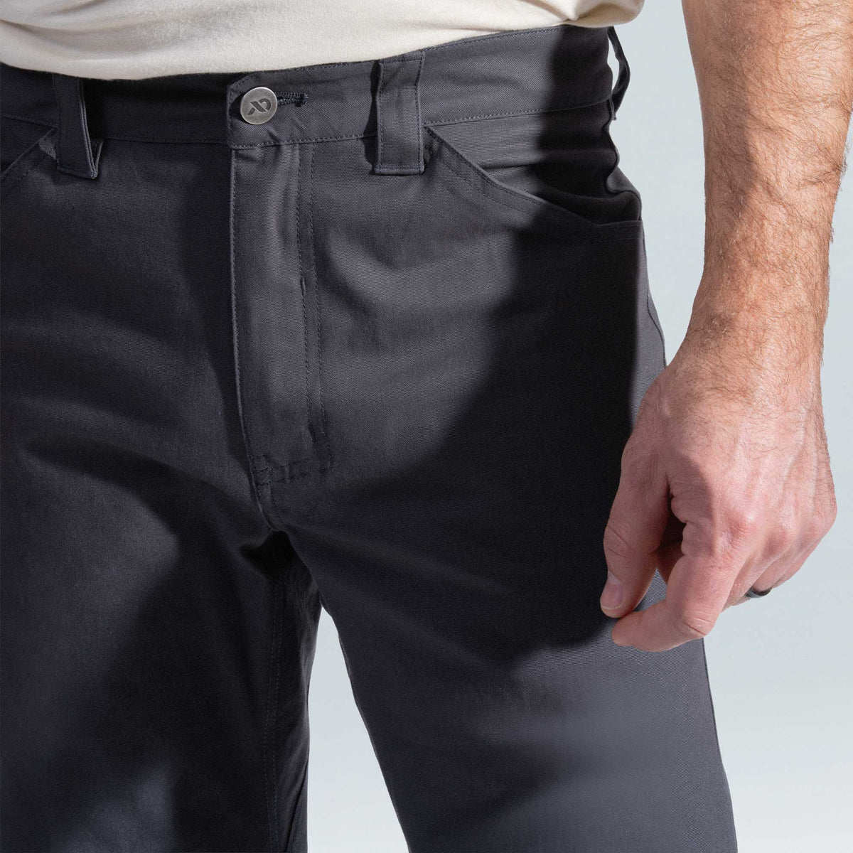 Person wearing dark pants with a plain background